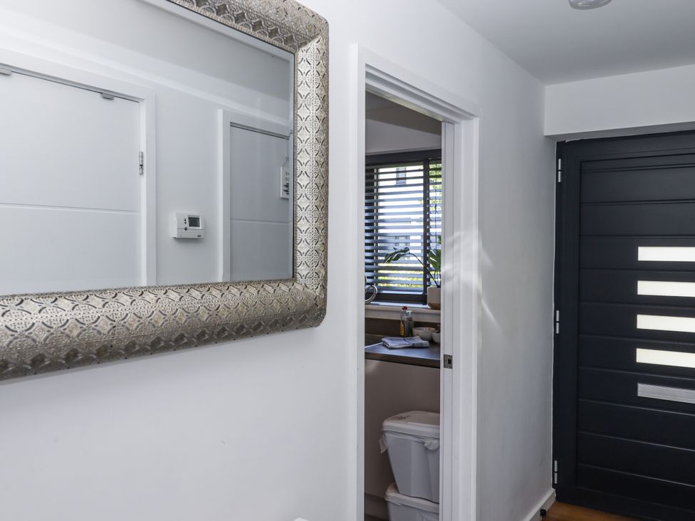 A hallway with a mirror and a doorway leading to the kitchen at Driftwood in Torquay