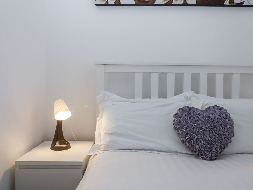 A bedroom with a bed and a lamp on a nightstand at Driftwood in Torquay