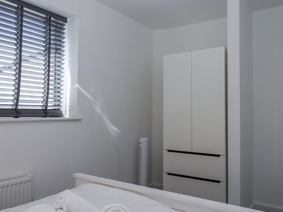A bedroom with a wardrobe and window at Driftwood in Torquay