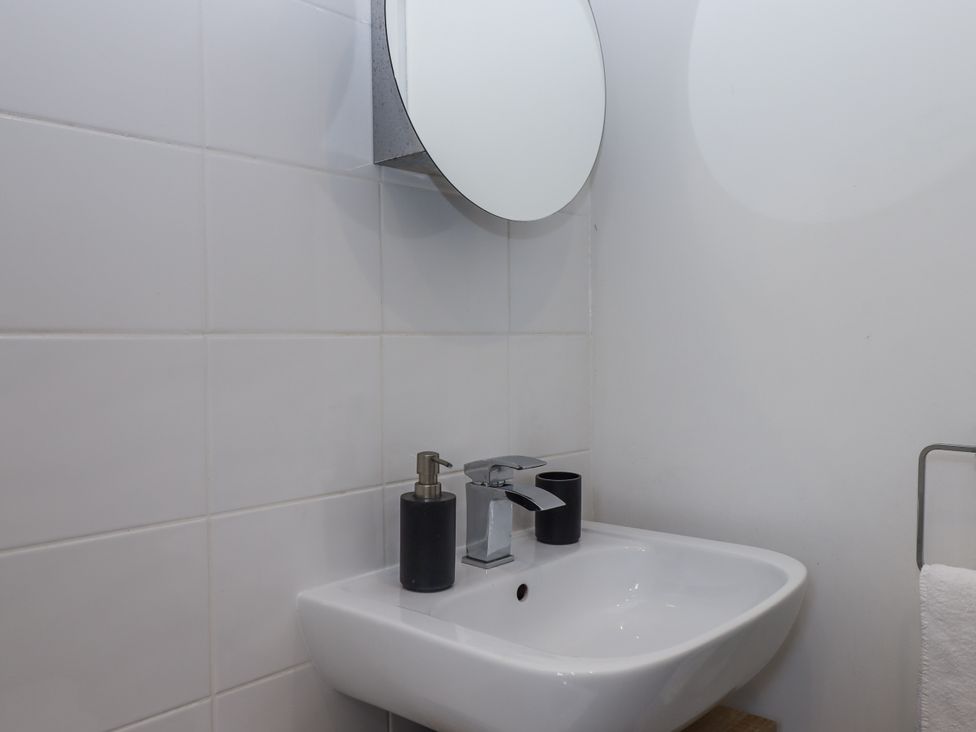A sink with a mirror and soap dispenser at Driftwood in Torquay