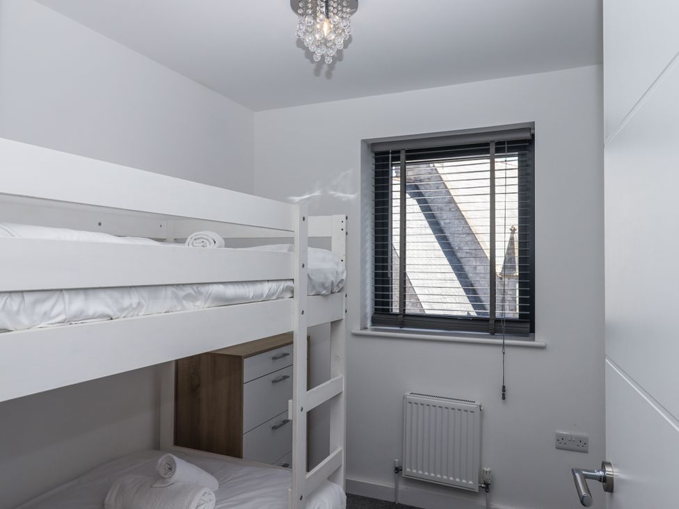 A bedroom with a bunk bed and a window at Driftwood in Torquay