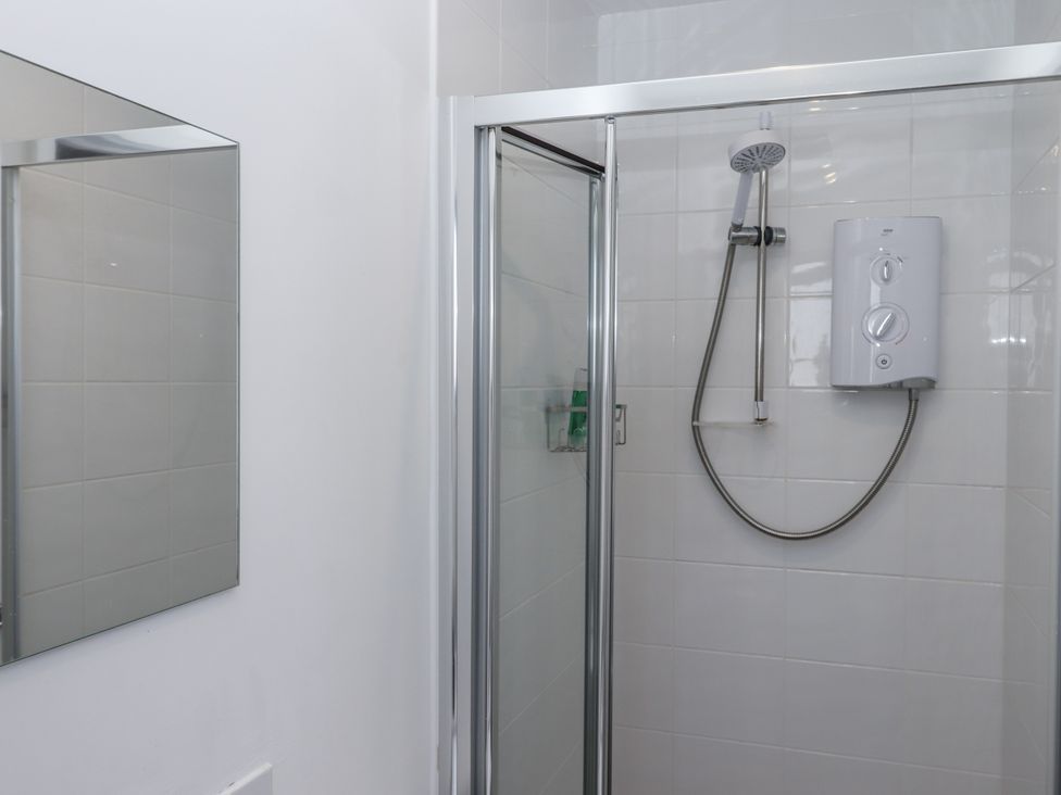 A shower with a water heater and mirror at Driftwood in Torquay