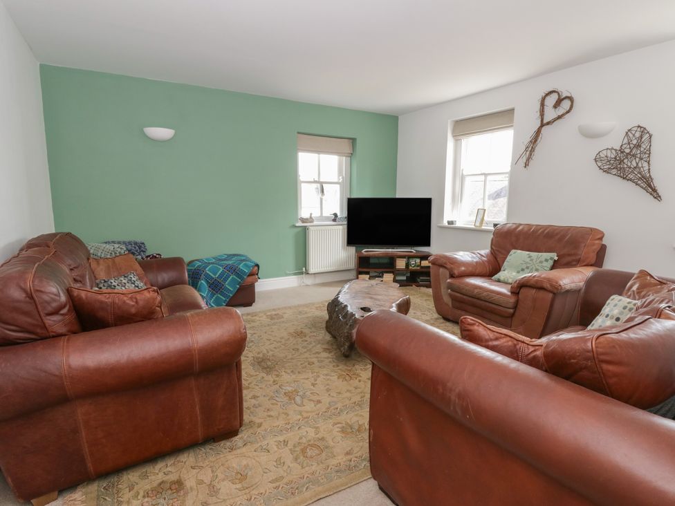 A living room with brown leather sofas and a television at Awen Ingli in Newport, Pembrokeshire