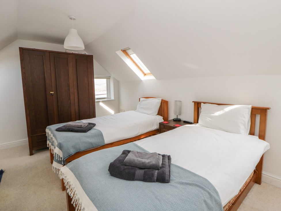 A bedroom with two beds and a wardrobe at Awen Ingli Newport, Pembrokeshire