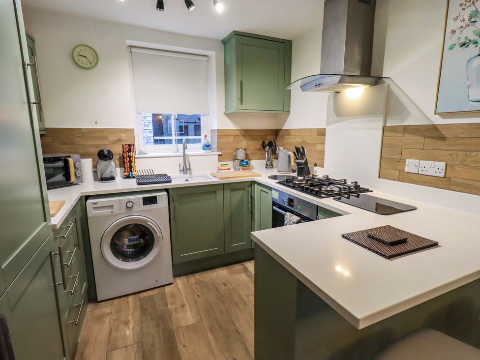 A kitchen with cabinets, stove, sink, and washing machine at 21 Entry Lane in Kendal