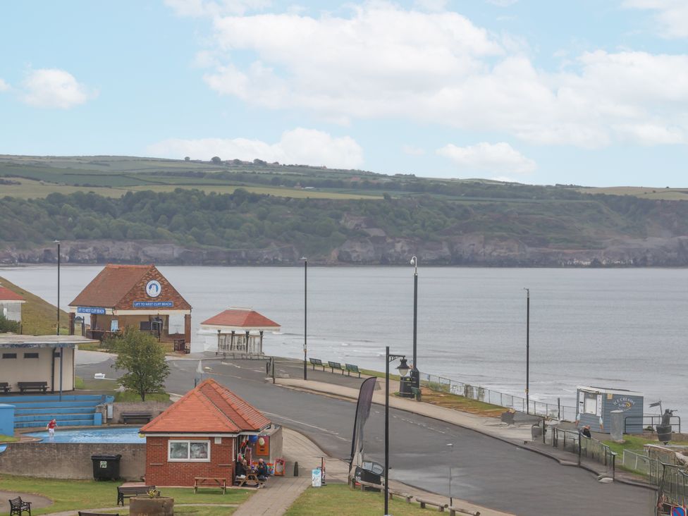 A view of the sea with buildings and benches at Sandsend View in Whitby