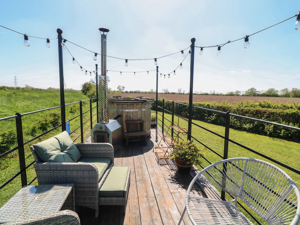 An outdoor terrace with seating and a hot tub at Sweet Caroline Shepherd’s Hut Low Marnham near Sutton-On-Trent