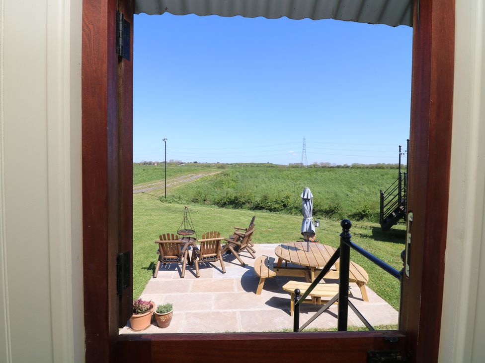 A view of a patio with chairs and a table from a doorway at Sweet Caroline Shepherd’s Hut Low Marnham near Sutton-On-Trent