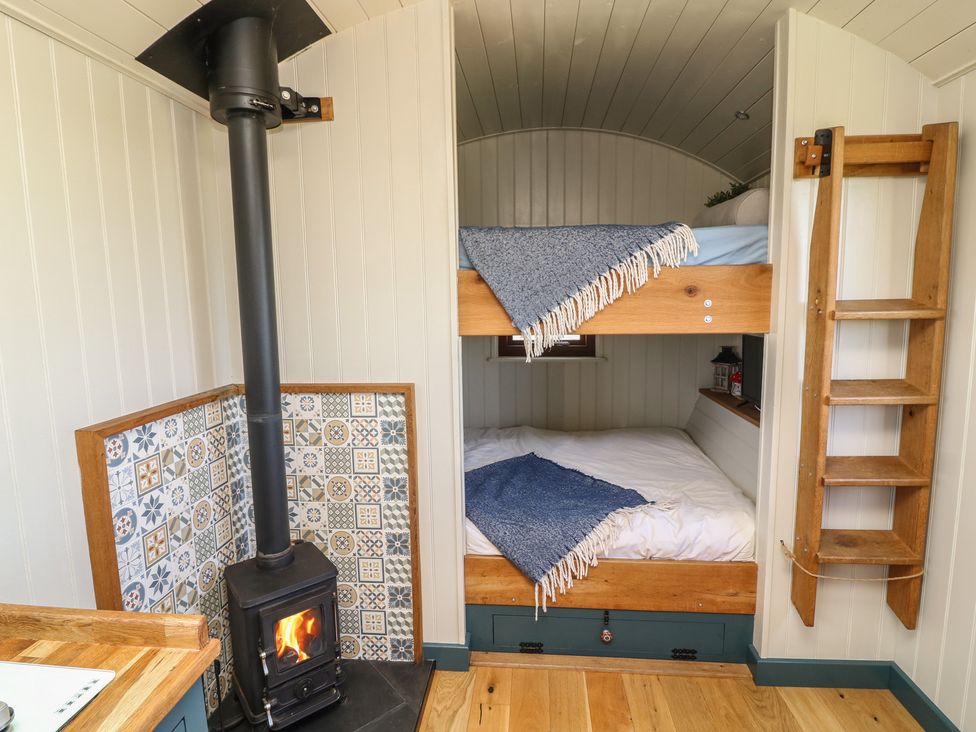 A bedroom with a bunk bed and wood-burning stove at Sweet Caroline Shepherd’s Hut Low Marnham near Sutton-On-Trent