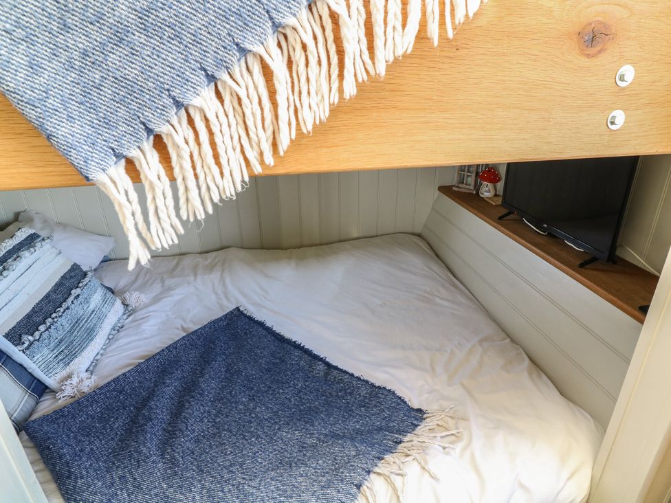 A sleeping area with a bed and television at Sweet Caroline Shepherd’s Hut Low Marnham near Sutton-On-Trent