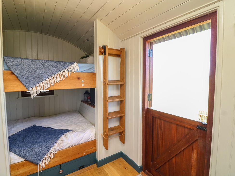 A bedroom with bunk beds and a wooden door at Sweet Caroline Shepherd’s Hut in Low Marnham near Sutton-On-Trent