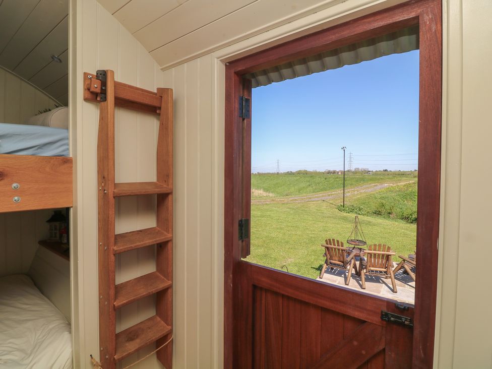 A view from inside a hut showing a wooden ladder and an outdoor seating area at Sweet Caroline Shepherd’s Hut Low Marnham near Sutton-On-Trent