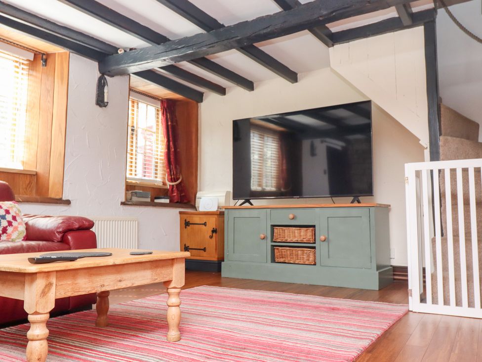A living room with a sofa and television stand at Cholmley Cottage in Ruswarp