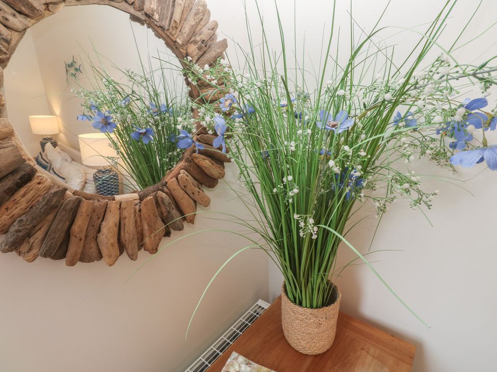 A vase with flowers on a table and a mirror in the living room at Upper Deck Truro
