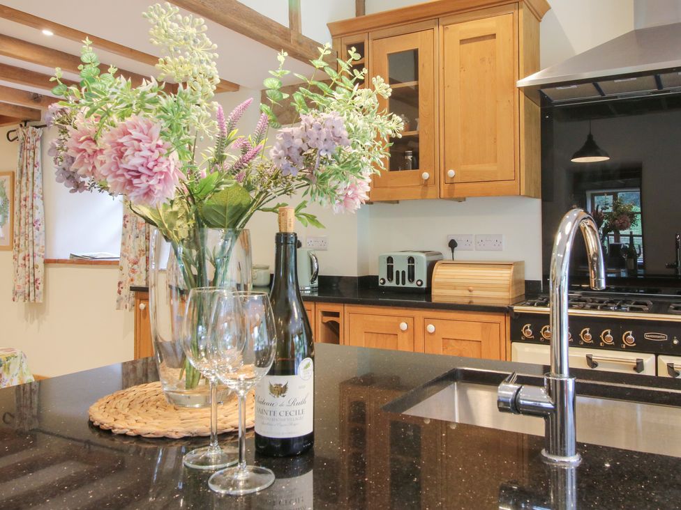 A kitchen with flowers, wine, and glasses at Grove Farm in Cardington near Church Stretton