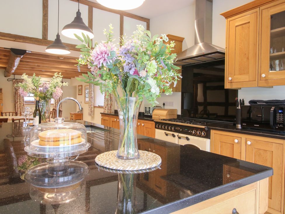 A kitchen with a floral arrangement and cake on the counter at Grove Farm near Church Stretton
