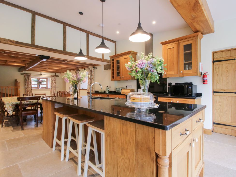 A kitchen with wooden cabinets and a dining table at Grove Farm Cardington near Church Stretton