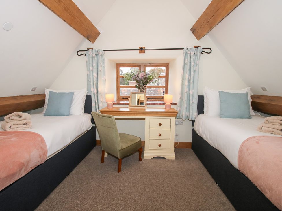 A bedroom with two single beds and a desk at Grove Farm in Cardington near Church Stretton