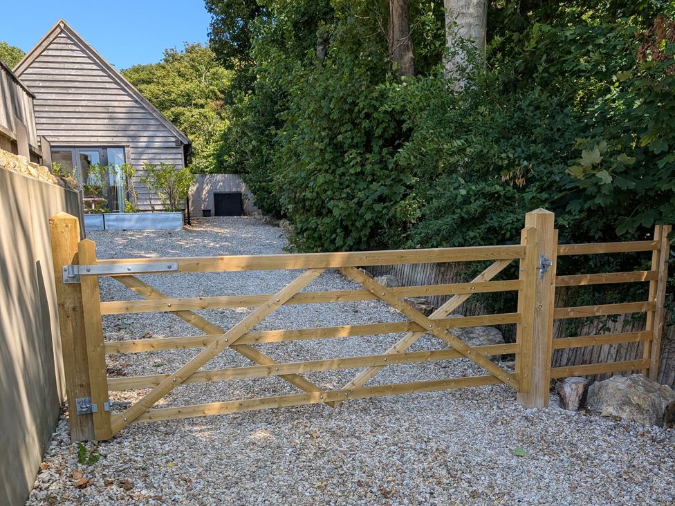 A wooden gate leading to a gravel driveway at Roman Lodge in Osmington