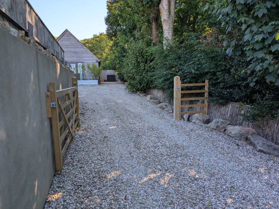 An outdoor area with a gravel path and wooden gates at Roman Lodge in Osmington
