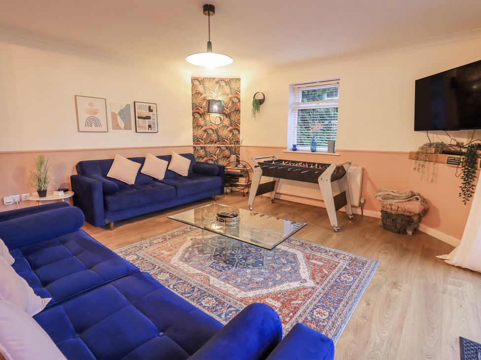A living room with blue sofas and a foosball table at 8 Beechwood Close in Bowness-On-Windermere