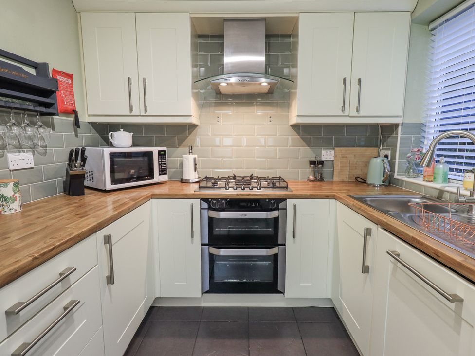 A kitchen with a stove, microwave, and sink at 8 Beechwood Close Bowness-On-Windermere