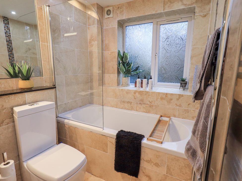 A bathroom with a bathtub and toilet at 8 Beechwood Close Bowness-On-Windermere