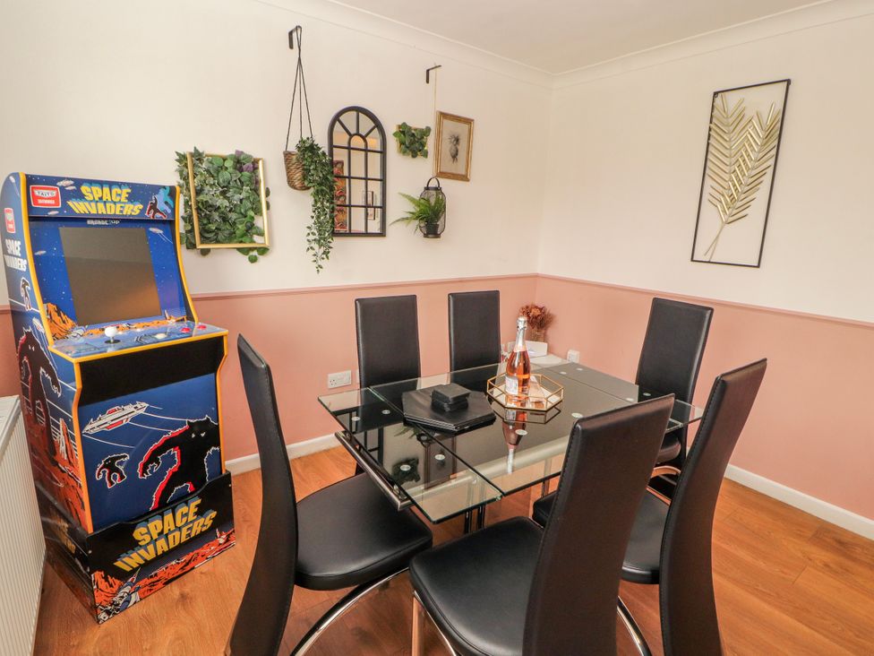 A dining room with a glass table and space invaders arcade machine at Lake View in Bowness-On-Windermere