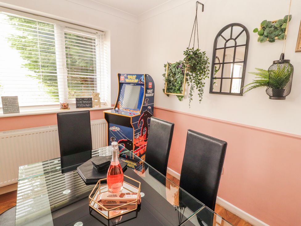 A dining room with an arcade game and a glass table at Lake View in Bowness-On-Windermere