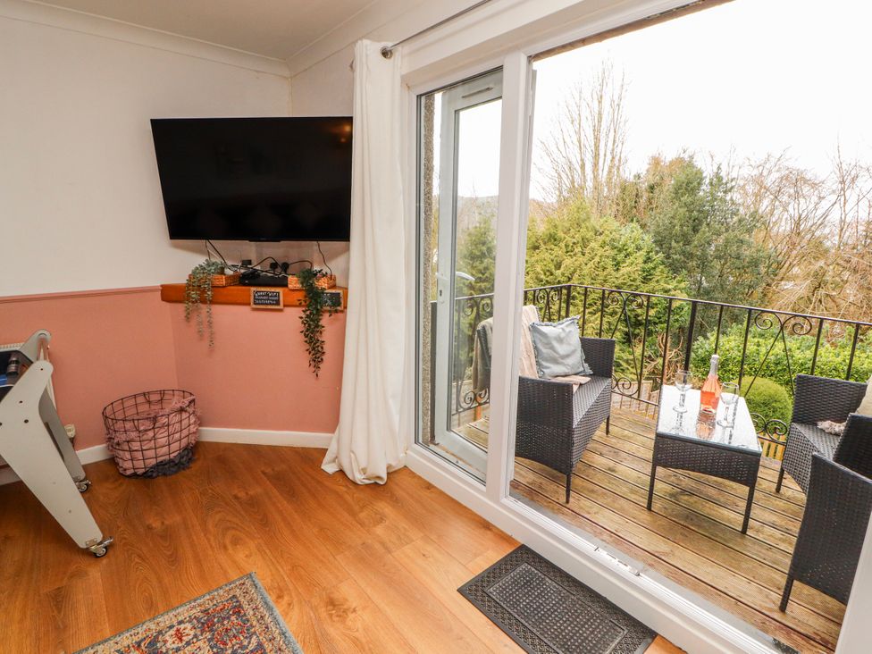 A living room with a television and a door leading to a balcony at Lake View in Bowness-On-Windermere