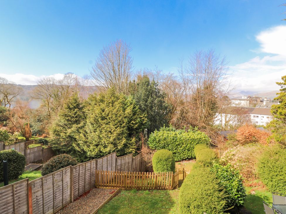 A garden with trees and a wooden fence at Lake View in Bowness-On-Windermere