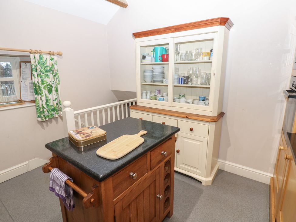 A kitchen with a wooden island and display cabinet at The Tithe Barn in Brignall near Barnard Castle