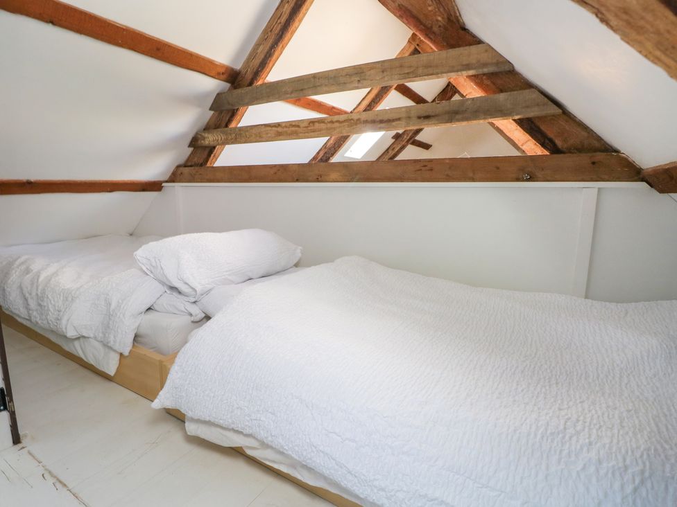 A small attic bedroom with two single beds and exposed wooden beams at Ty Mellen in Dinas Cross