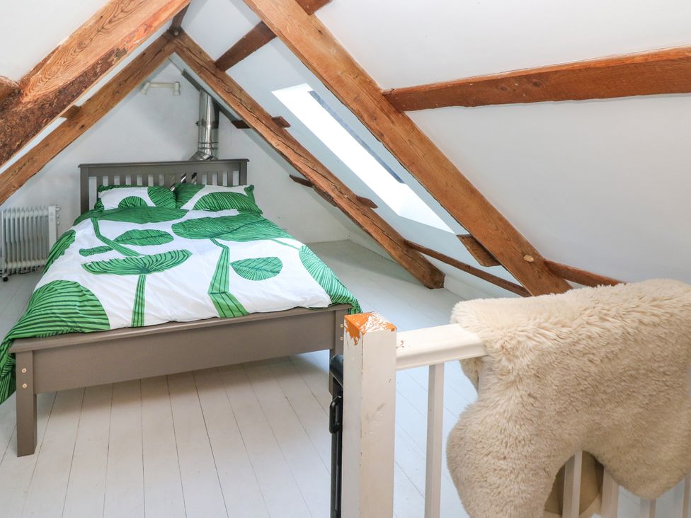 A bedroom with a grey bed and green patterned bedding under exposed wooden beams at Ty Mellen in Dinas Cross