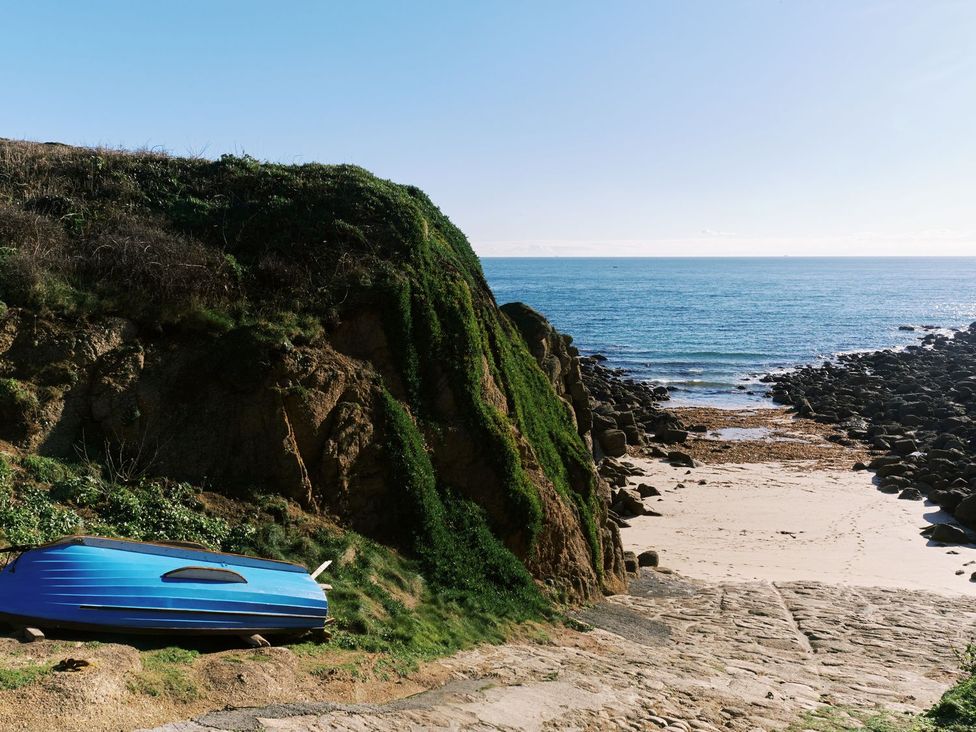 A beach scene with a blue boat near the water at Faraway Cottage St. Levan near Porthgwarra