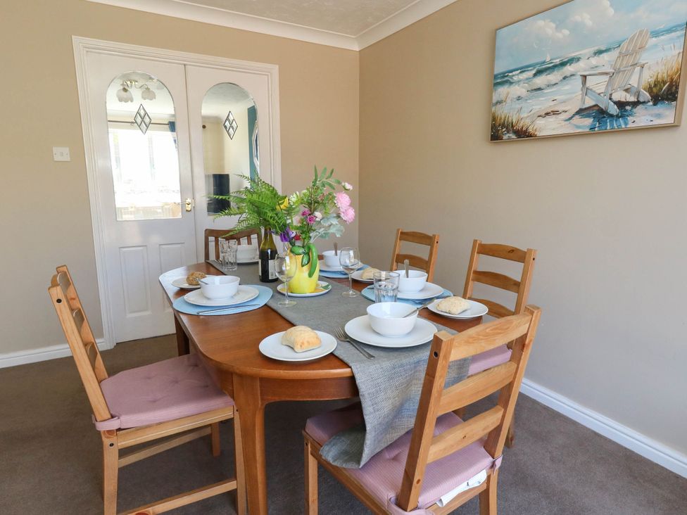 A dining room with a table set for meals at Cove Cottage in Weymouth