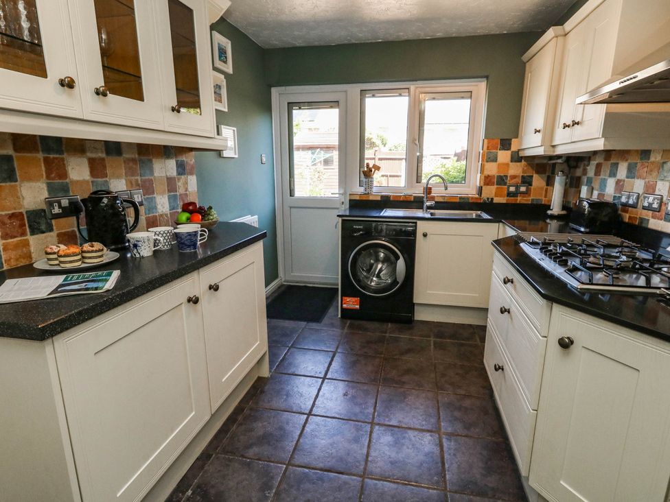 A kitchen with a washing machine and cooker at Cove Cottage Weymouth