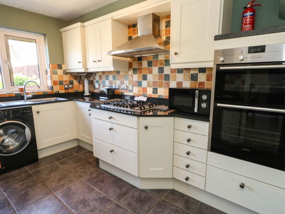 A kitchen with appliances and cabinets at Cove Cottage Weymouth