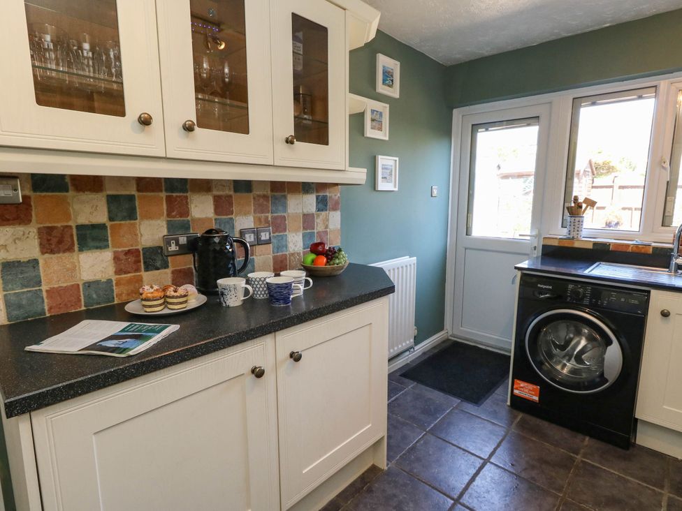 A kitchen with cabinets and a washing machine at Cove Cottage in Weymouth