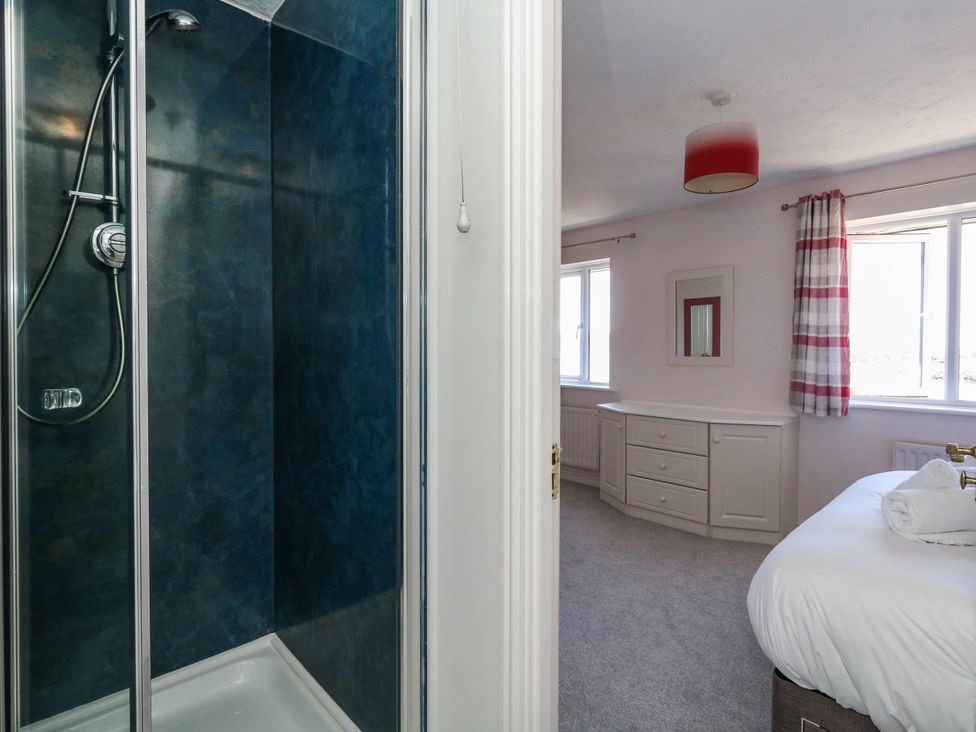 A shower and bedroom with storage at Cove Cottage in Weymouth