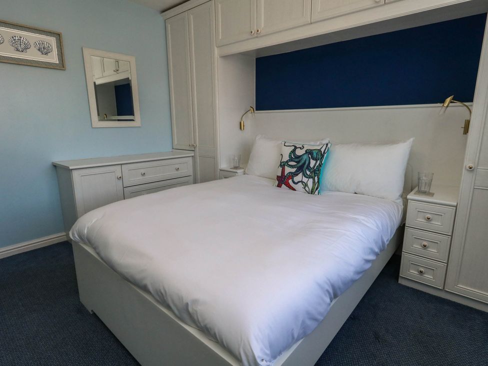 A bedroom with a bed and bedside tables at Cove Cottage in Weymouth
