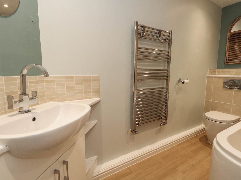 A bathroom with a sink, toilet, and towel rail at Cove Cottage in Weymouth