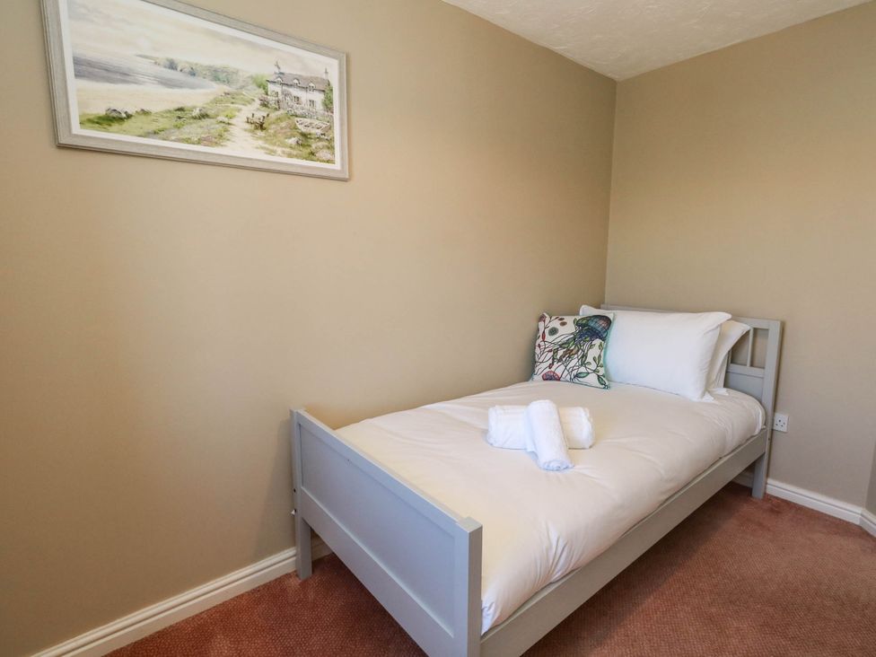 A bedroom with a single bed and wall art at Cove Cottage in Weymouth