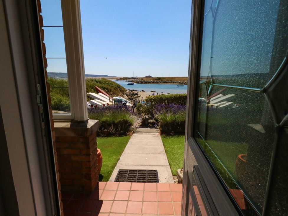 A view from a doorway towards a pathway and water at Cove Cottage in Weymouth