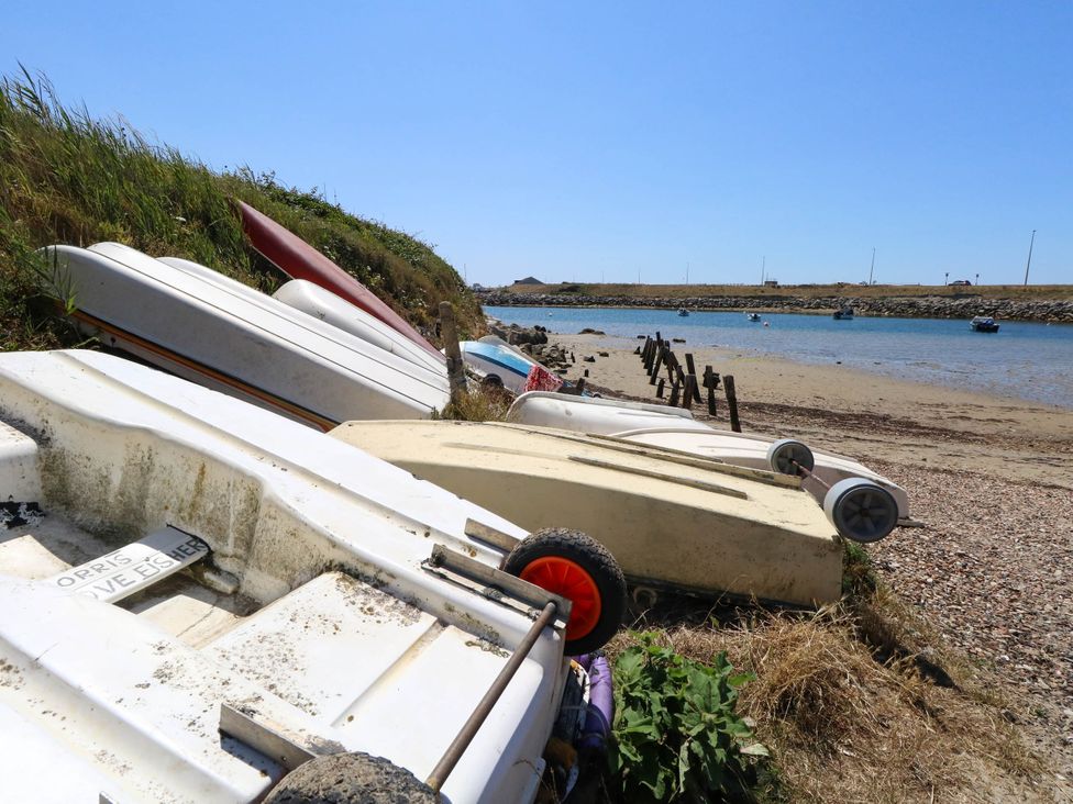 A beach with several boats on sand at Cove Cottage Weymouth