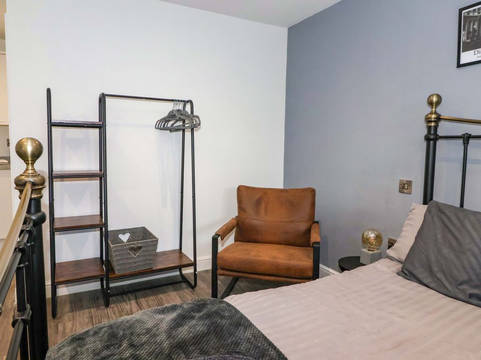 A bedroom with a bed, armchair, and clothes rack at Chalet 2 in East Heslerton near Sherburn