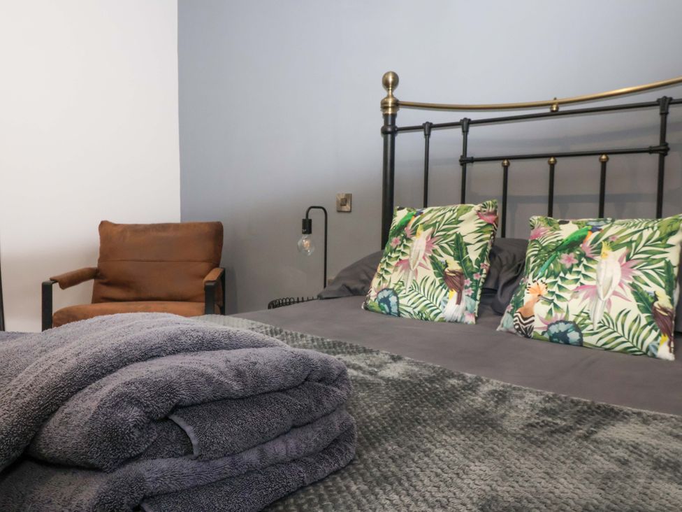 A bedroom with a bed, armchair, and cushions at Chalet 4 in East Heslerton near Sherburn