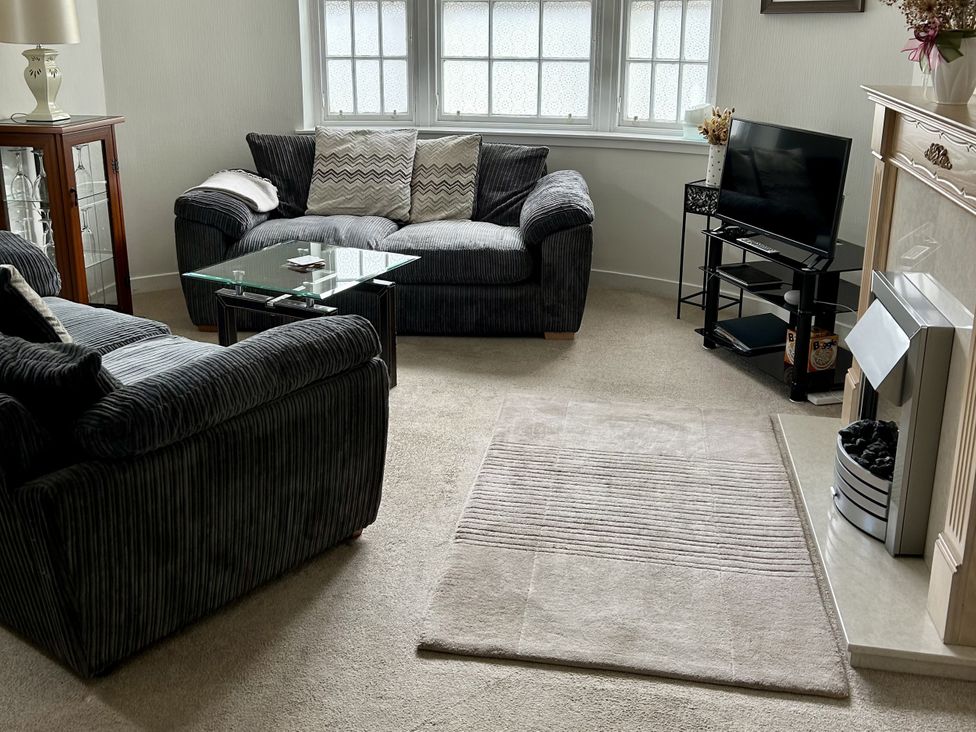 A living room with a sofa, coffee table, and television at The Toll House in Melrose