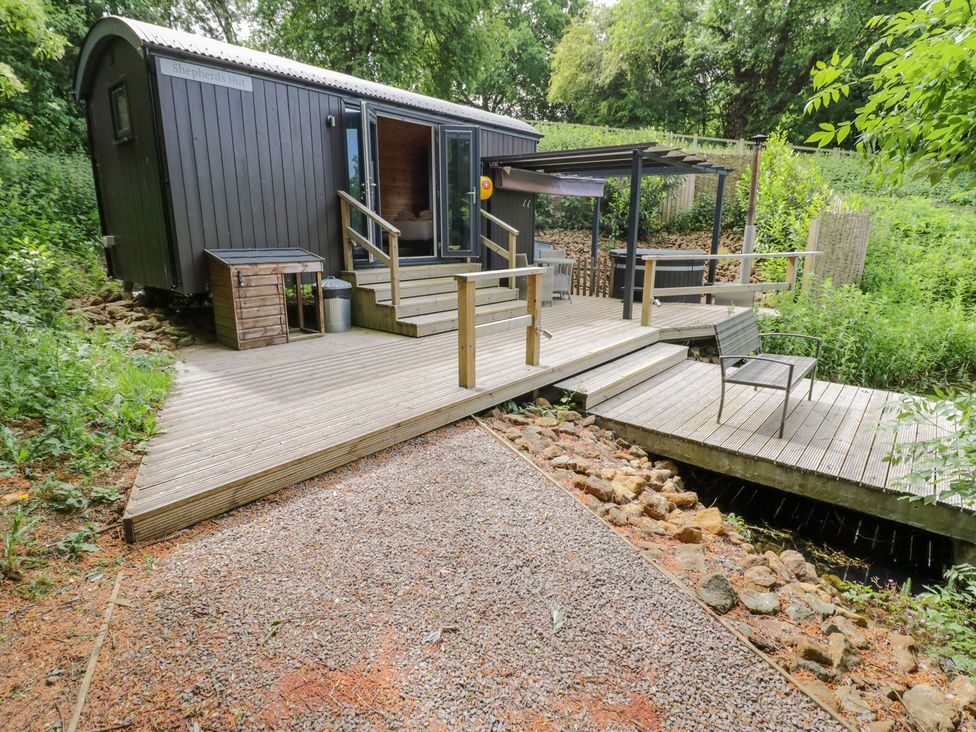 A shepherd's hut with decking and steps at The Shepherds Hut at Bridge Lake Farm & Fishery Chacombe