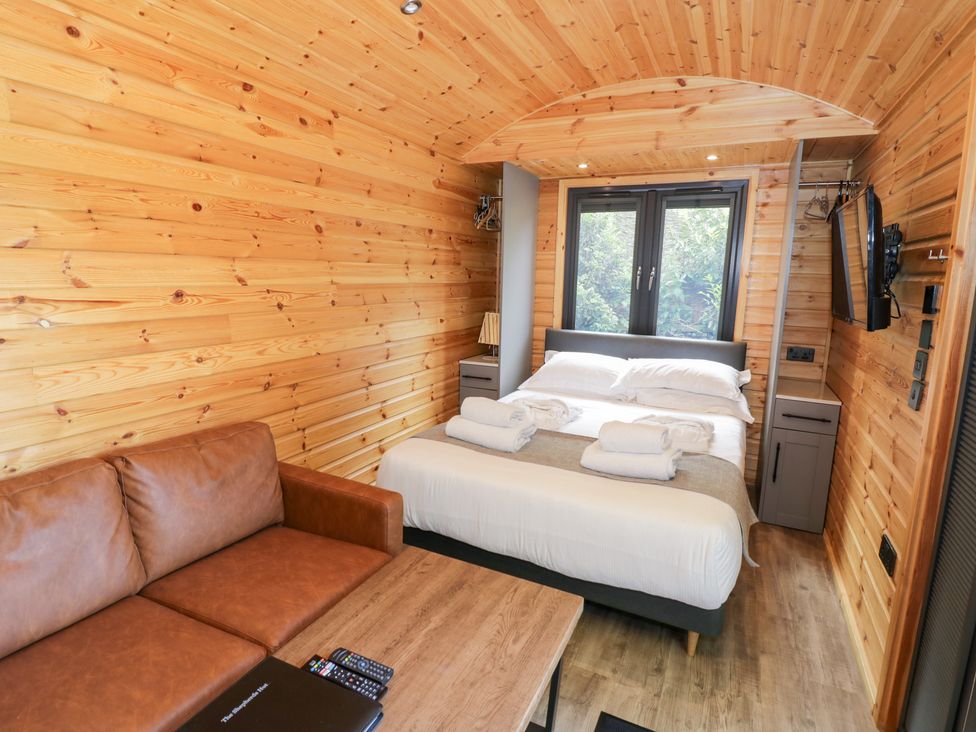 A bedroom with a bed and sofa at The Shepherds Hut at Bridge Lake Farm & Fishery Chacombe